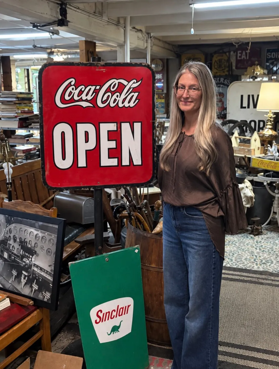 Shop owner standing beside vintage enamel signs