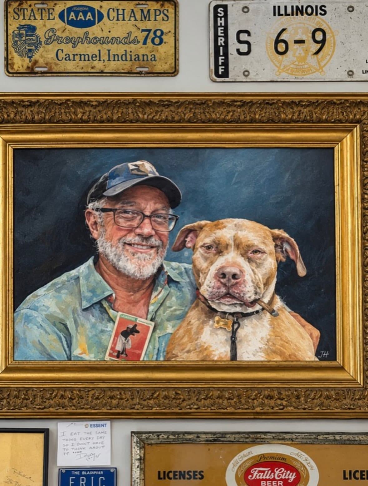 Gold-framed original portrait painting of a man and his dog surrounded by vintage license plates at Vintage Finds Antiques